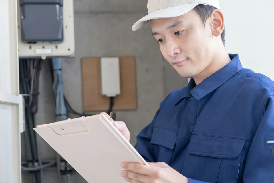 設備のそばで確認事項を記録する作業員